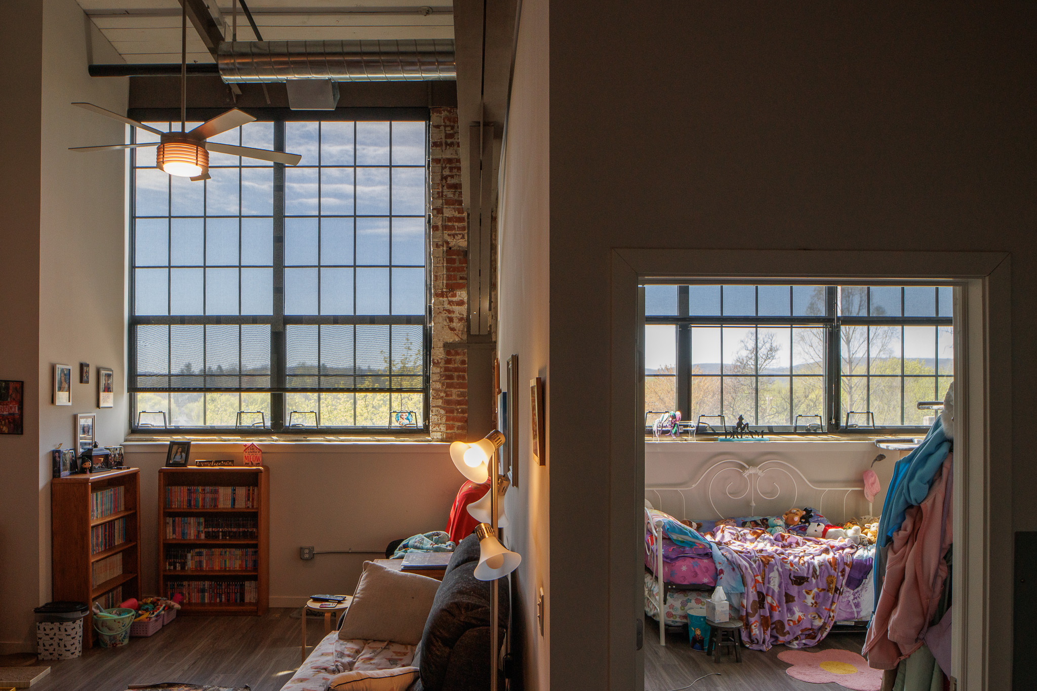 Child-friendly living room or playroom with wooden bookshelves full of colorful children's books, toys, and baskets near a window
